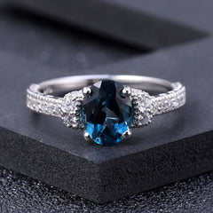 Anillo opulento con halo de topacio azul Londres y circonita cúbica transparente