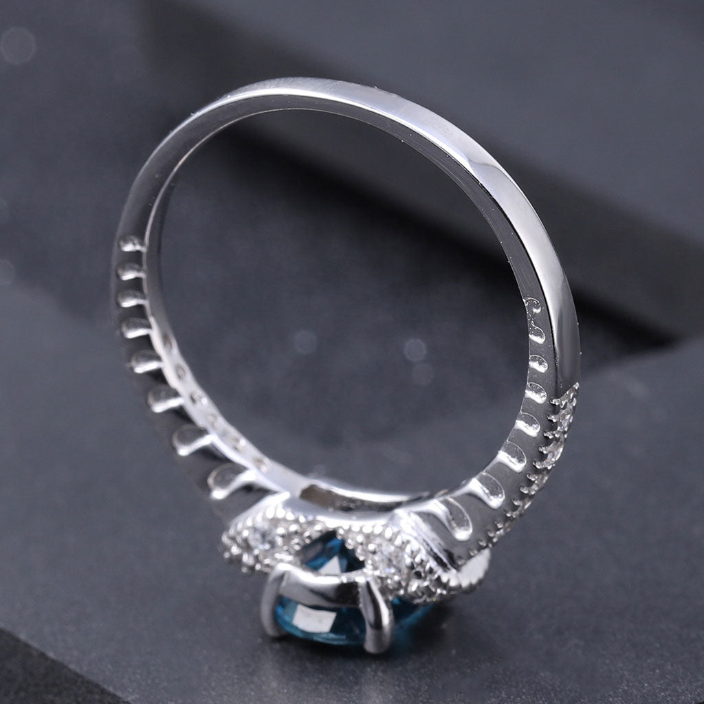 Anillo opulento con halo de topacio azul Londres y circonita cúbica transparente